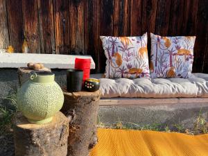 a couch sitting on a wooden bench with pillows at Jolie cabane avec jacuzzi pour les amoureux de la nature in Tullins