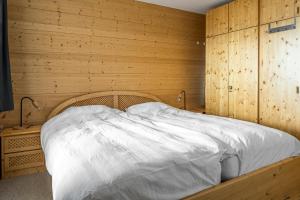 - une chambre avec un lit et un mur en bois dans l'établissement Fata Morgana 2, à Bettmeralp