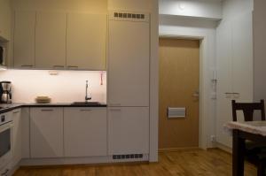 a kitchen with white cabinets and a door to a room at Lahti Hietaneilikka Apartments in Lahti