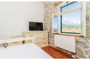 a bedroom with a bed and a tv and a window at Villa Heart of Stone in Ploče