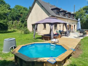 una piscina con terraza y sombrilla en Firs Lake, en Ruillé-le-Gravelais