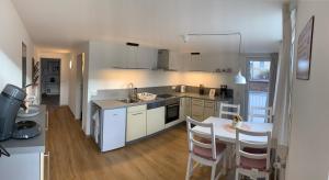 布雷根茨Chalet zum See的厨房配有白色橱柜和桌椅 更多5张照片