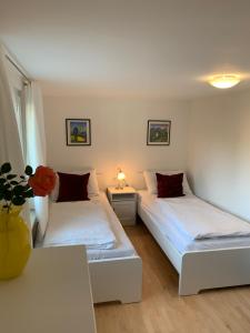 Cette chambre comprend deux lits et une table avec un vase. dans l'établissement Chalet zum See, à Bregenz