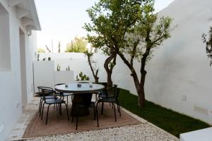 un patio con mesa, sillas y un árbol en Le Carasse Boutique Hotel en Mola di Bari