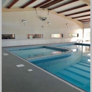 a large swimming pool with blue water in a building at Pebbles Seaside Lodge in Kent