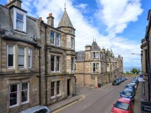 an old street with cars parked in front of buildings at Andrean House, St Andrews in St. Andrews