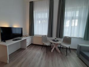 ein Wohnzimmer mit Fernseher, Tisch und Stühlen in der Unterkunft Gasthaus Brockenhėxe mit Restaurant & Café in Schierke + 20 Fotos