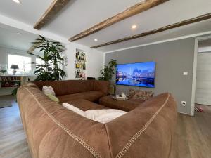 a living room with a brown couch and a tv at Willingenvakanties,Modern Quality Apartments Restyled nov 2022 WILLINGEN 2023 in Willingen