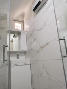 a white bathroom with a sink and a mirror at 007 Apartments - Strumica, Macedonia in Strumica