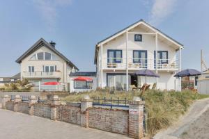 una casa blanca con sombrillas rojas delante en CHALET FOR 2 AT THE BEACH en Zandvoort