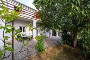 a house with a tree and a table and chairs at Apartment Eva in Maslenica