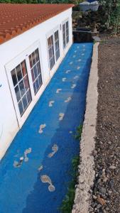 una passerella blu con impronte di piedi di fronte a una casa di Finca Cosmos a El Paso