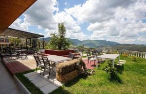 a patio with tables and chairs with mountains in the background at Rozmarine in Pëllumbas