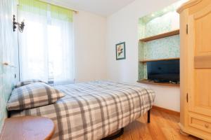 Dormitorio pequeño con cama y TV en Patrioti 51 - Asiago Centro, en Asiago