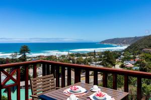 a table on a balcony with a view of the ocean at Luxury Studio - Panoramic Ocean Views - Fast Wifi in Wilderness