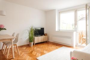 a white living room with a table and a television at White Apartment in Ljubljana