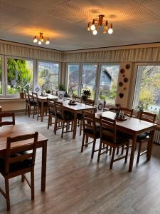 ein Esszimmer mit Tischen, Stühlen und Fenstern in der Unterkunft Casa Milix - Bed & Breakfast in Winterberg