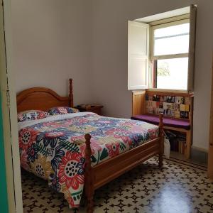 a bedroom with a bed with a colorful comforter and a window at Ratones de Biblioteca in La Laguna