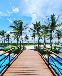 a wooden bridge over a body of water with palm trees at Apto de luxo no Golfville Ideal para família e home office Prox do Beach Park in Aquiraz
