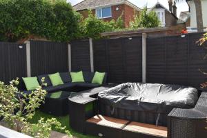 a backyard with a couch and a fence at Amazing seaside home 5mins from beach with HOT TUB in Broadstairs