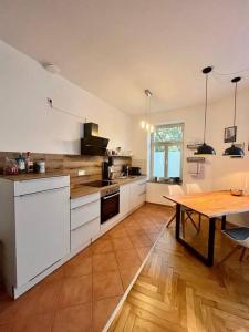 una cocina con armarios blancos y una mesa con suelo de madera. en FirstClass 2R_Apartment in Leipzig en Leipzig