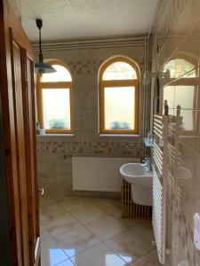 a bathroom with a tub and a sink and two windows at Bolla Nyaralóház in Hegyhátszentjakab