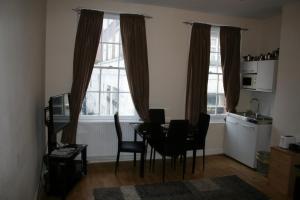 a dining room with a table and chairs and two windows at Mayfair Flat in London