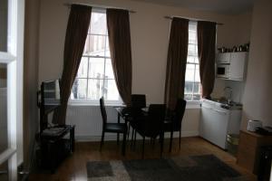 sala de estar con mesa, sillas y 2 ventanas en Mayfair Flat, en Londres