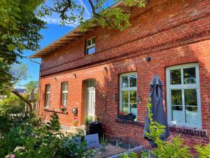 a brick house with an umbrella in front of it at Wohnung Luv - Alte Schule in Glowe