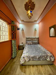 Un dormitorio con una cama con paredes de color naranja y una lámpara de araña. en Riad Najiba, en Rabat