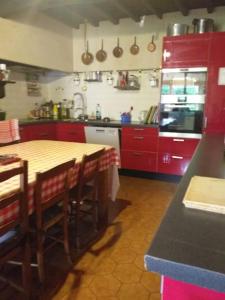 uma cozinha com armários vermelhos, uma mesa e cadeiras em le repos du voyageur em Estadens