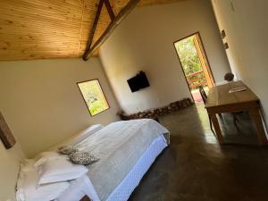 a bedroom with a bed and a desk and a window at Pousada Vale dos Diamantes in Vargem Bonita