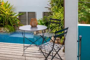 einen Tisch und Stühle auf einer Veranda mit Pool in der Unterkunft Curaçao Gardens in Willemstad