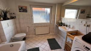 a bathroom with a sink toilet and a window at Schöne Wohnung mit Blick ins Grüne Messenah Exhibition apartment in Sehnde +9 photos