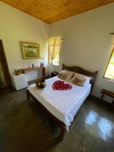 a bedroom with a large bed with a red flower on it at Pousada Vale dos Diamantes in Vargem Bonita