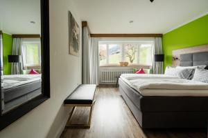 twee bedden in een kamer met groene muren en een spiegel bij Gästehaus Dauser in Obermaiselstein