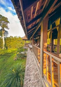 une terrasse couverte en bois d'une maison avec vue sur un champ dans l'établissement Ma Maison Khaoyai, à Ban Sap Bon