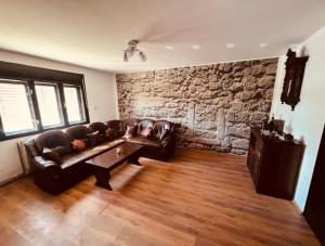 a living room with a leather couch and a stone wall at Countryside house with 3 bedrooms in Bonţeşti