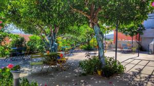 a patio with tables and chairs and trees at Aethra Boutique Rooms in Nafplio