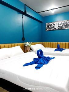 a room with three beds with blue ribbons on them at Airport Mini Hostel at Don Muang Airport in Ban Don Muang