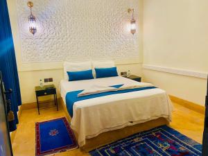 a bedroom with a large bed with blue pillows at Auberge Kasbah Ennakhile in Nkob