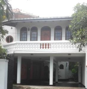 un gran edificio blanco con un porche blanco en Ceylon Travel and Stay Lodge, en Battaramulla