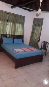 1 dormitorio con cama con sábanas azules y silla en Ceylon Travel and Stay Lodge, en Battaramulla