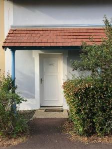 un edificio con una puerta blanca y un techo rojo en Le Hameau du lac, en Marciac