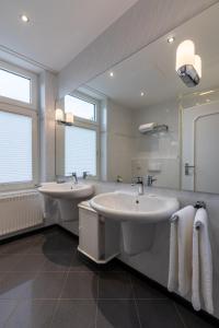 een badkamer met 2 wastafels en een grote spiegel bij Hotel Wittekindsquelle in Bad Oeynhausen