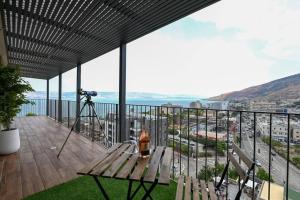 un balcone con panca in legno e macchina fotografica di L.T.D- MY VIEW. 2 bedroom apartment by the lake. a Tiberias