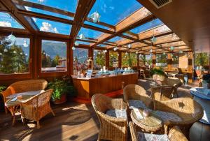 einen Wintergarten mit Tischen und Stühlen und eine Bar in der Unterkunft Luna Wellness Hotel in Folgarida