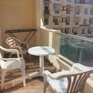 a balcony with chairs and a table and a table at Florenza Khamsin 1 bedroom apartment with swimming pool view in Hurghada