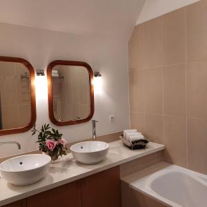 a bathroom with two sinks and two mirrors at Chateau de Vaux in Gesnes-le-Gandelin