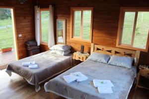 Duas camas num quarto com paredes e janelas de madeira em Cabana Leão Baio em Urubici